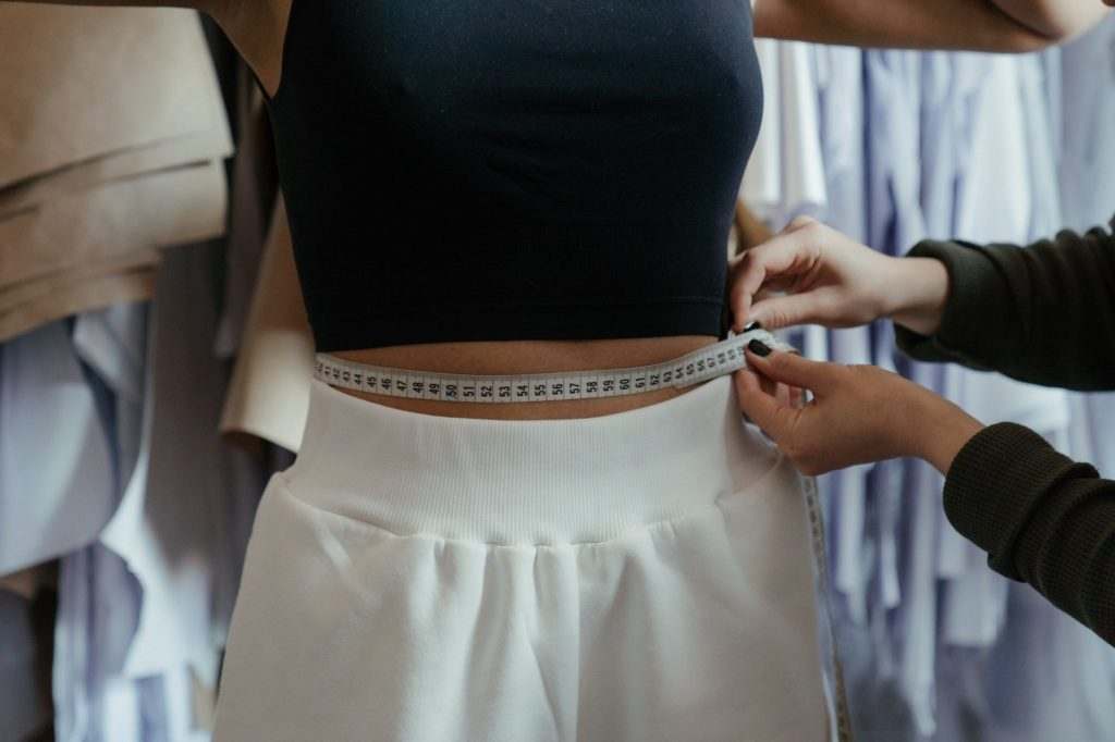 Female and white shorts getting her waist measurement