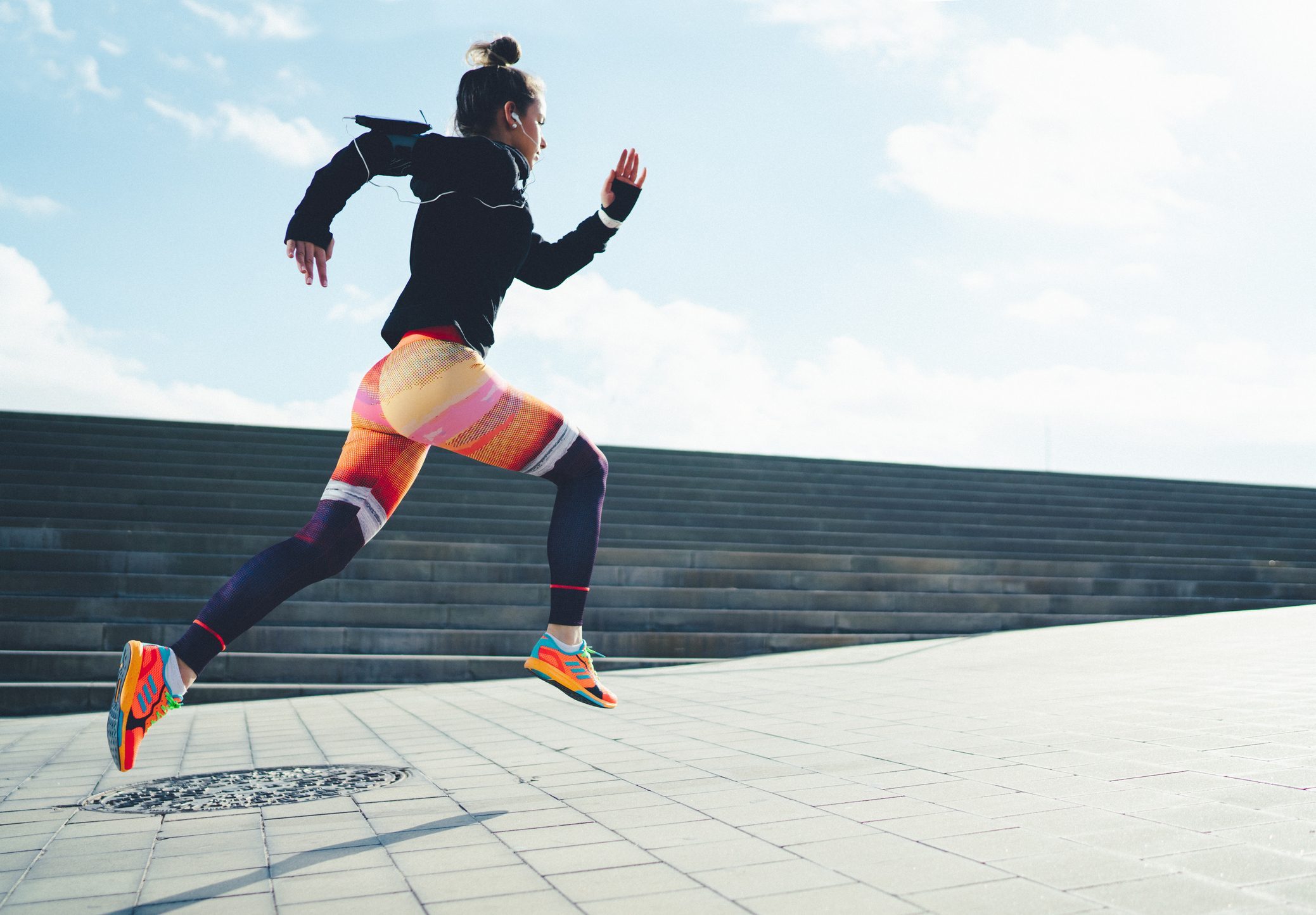 A woman is sporting the athleisure trend while running on a set of steps.