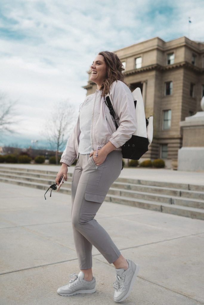 A woman embraces the athleisure trend, sporting grey cargo pants and a backpack.