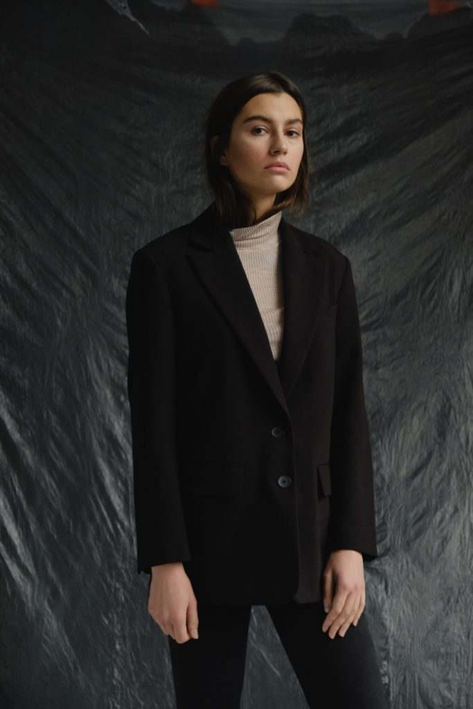 A woman sporting an athleisure trend with a black blazer and turtleneck.
