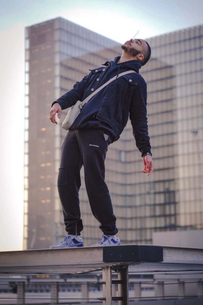 A man showcasing the athleisure trend on a skateboard atop a building.