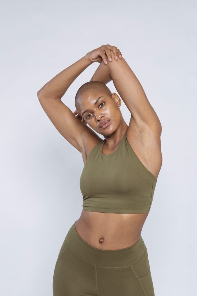 A woman embracing the athleisure trend while wearing a green sports bra and leggings.