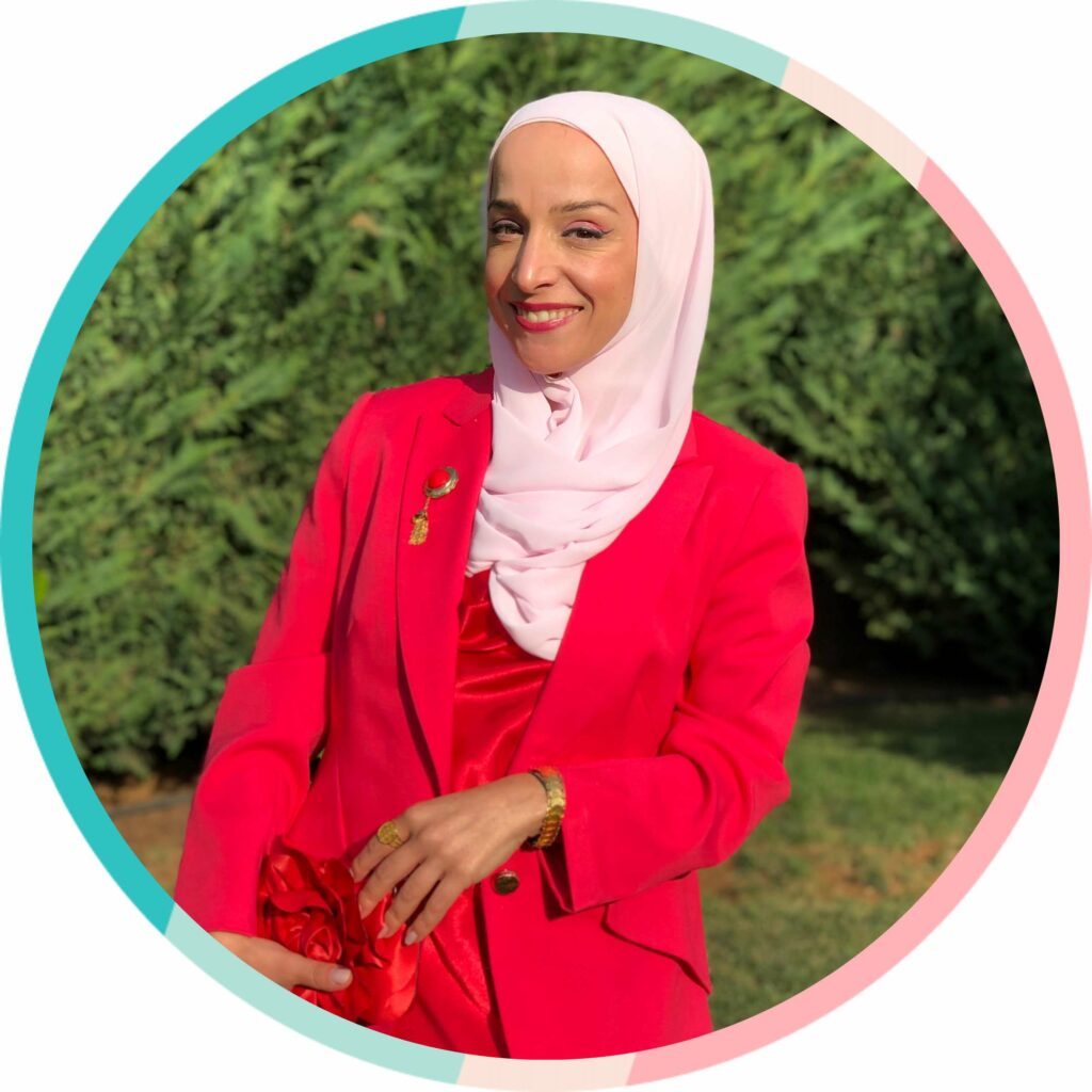 A woman in a red blazer and hijab confidently posing for a photo, displaying her impeccable style as she seeks guidance from her size wise closet coach.